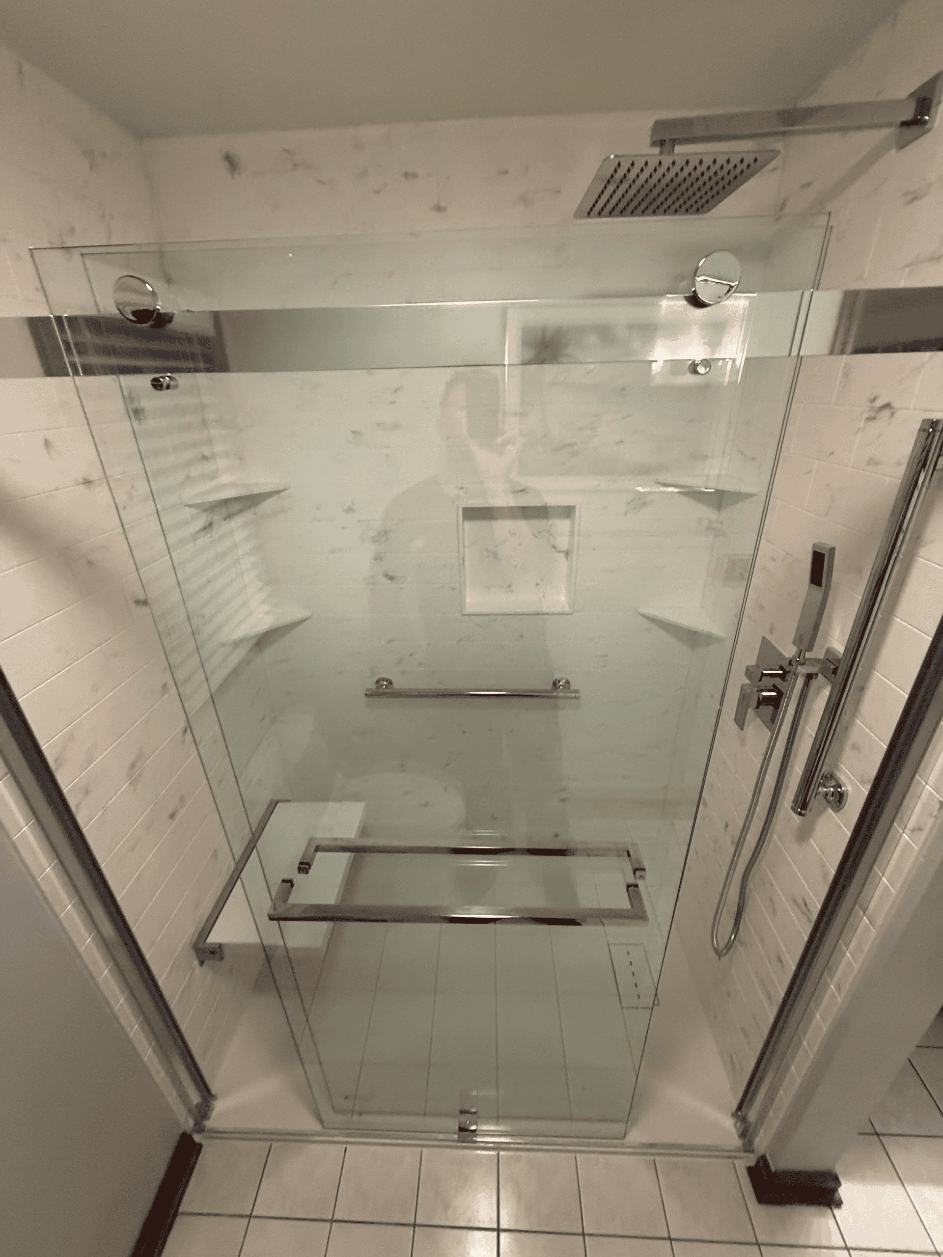 Accessible shower with glass enclosure and grab bars for safety.