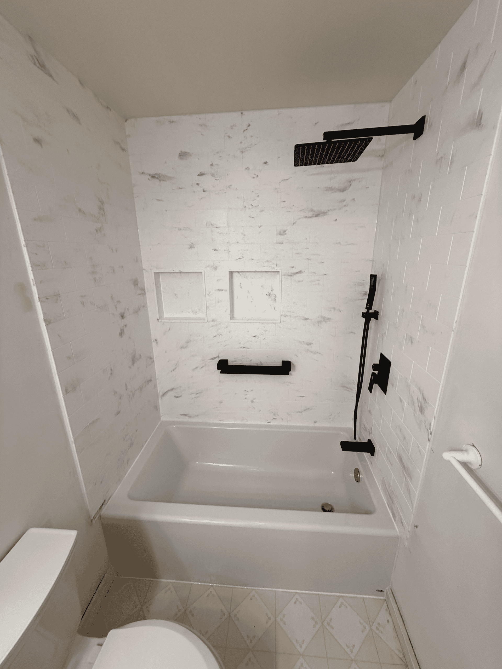 Shower with black fixtures and white tiled walls in a contemporary bathroom setting.