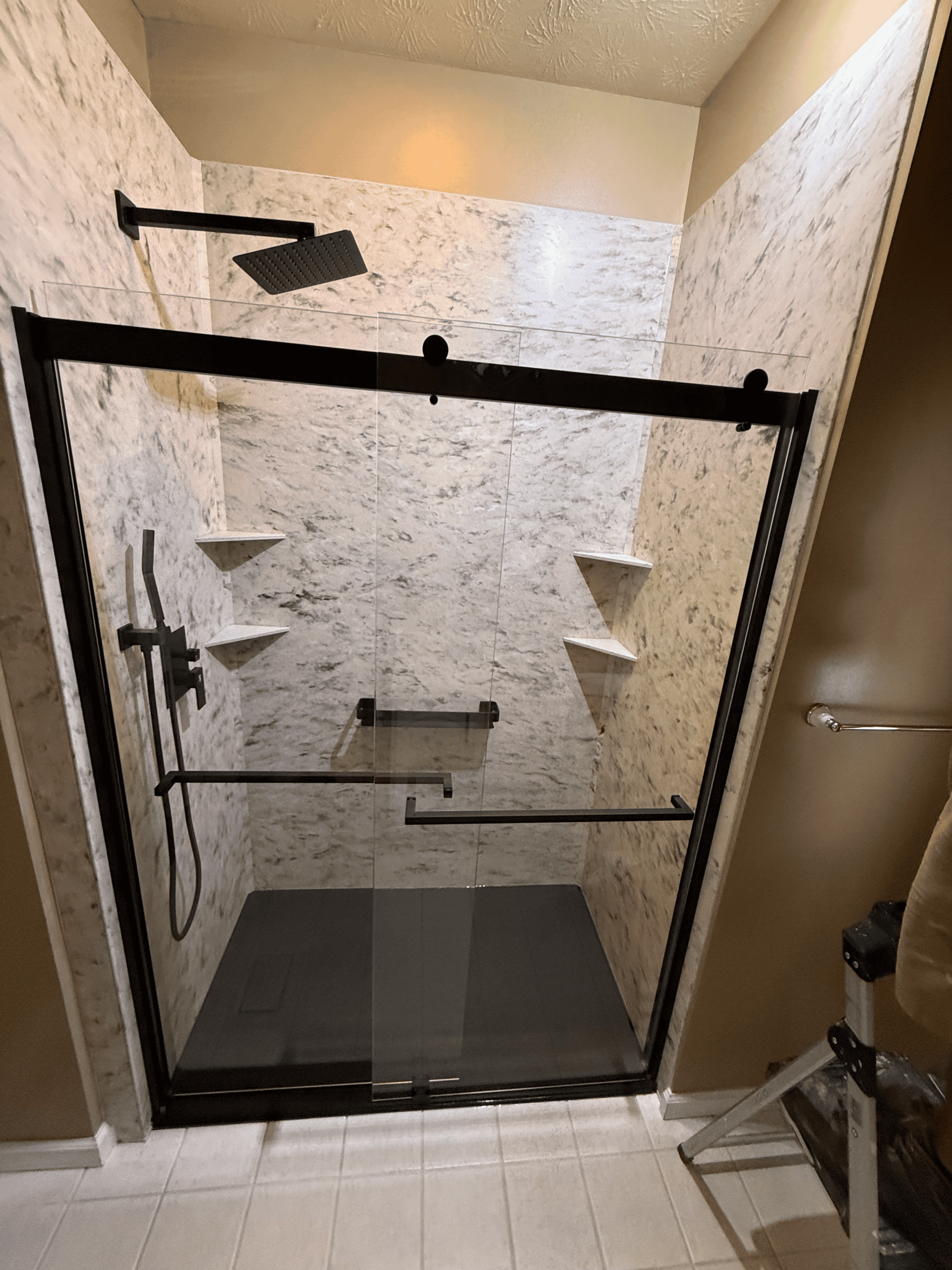 Modern glass shower door with black frame and built-in shelves.