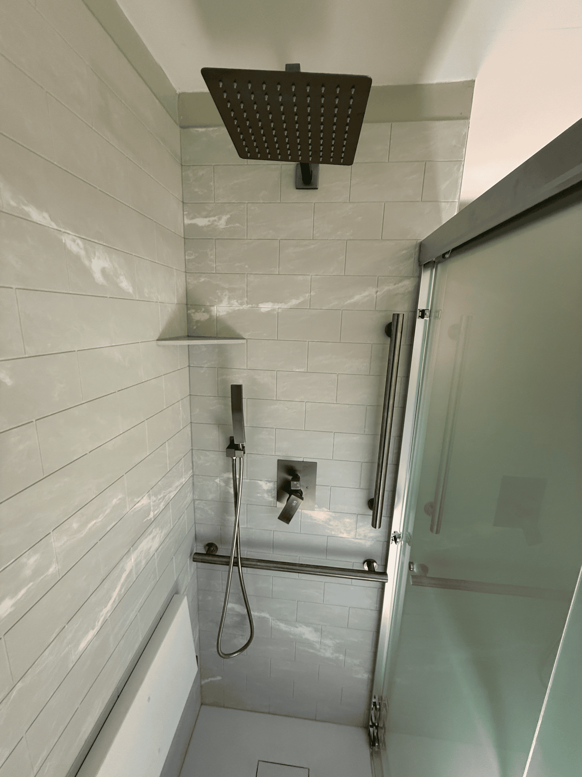 In shower with rainfall head and glass door.