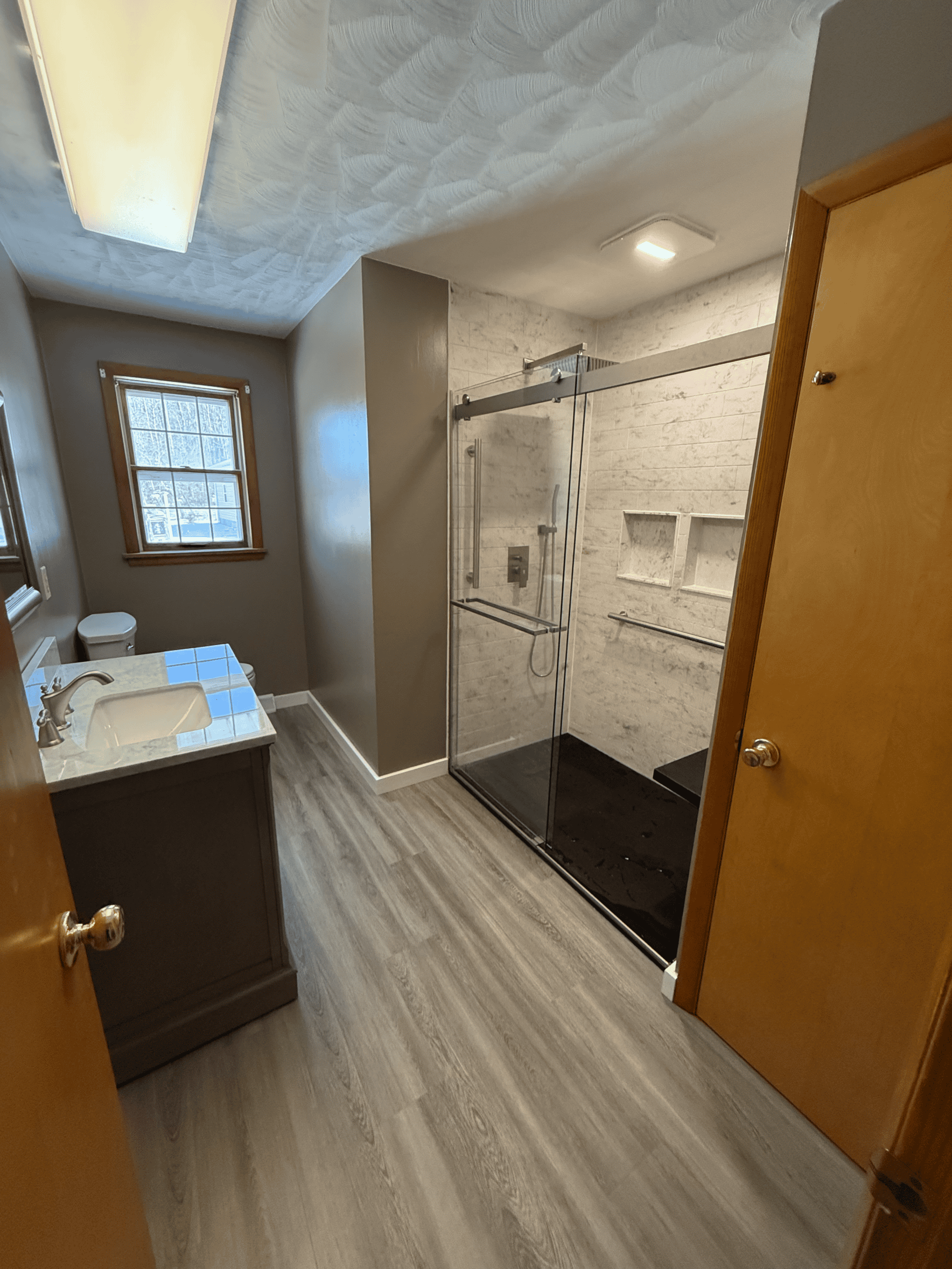 Modern bathroom with glass shower enclosure, vanity, and natural light.