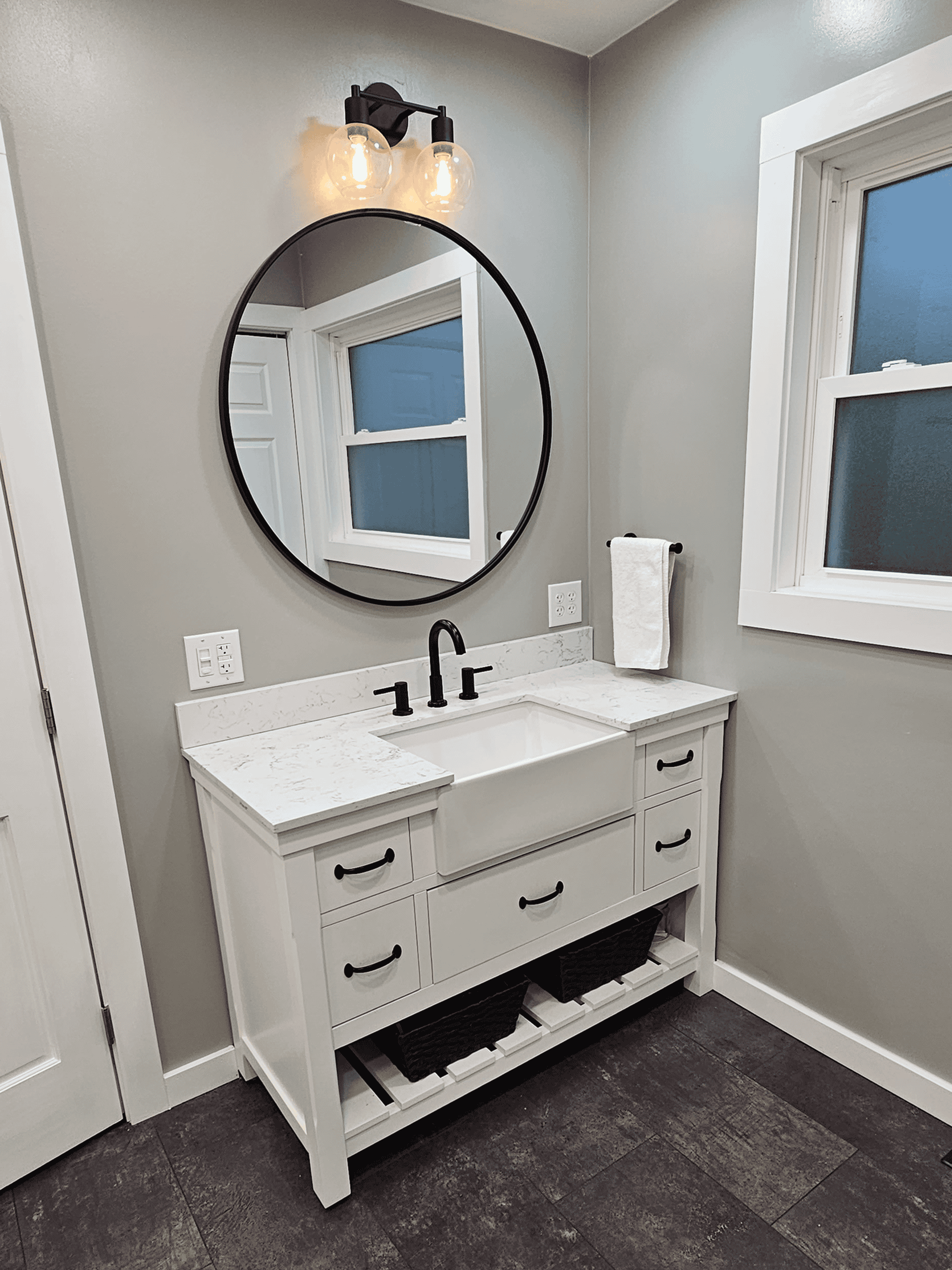 Bathroom vanity with white cabinetry and black hardware.