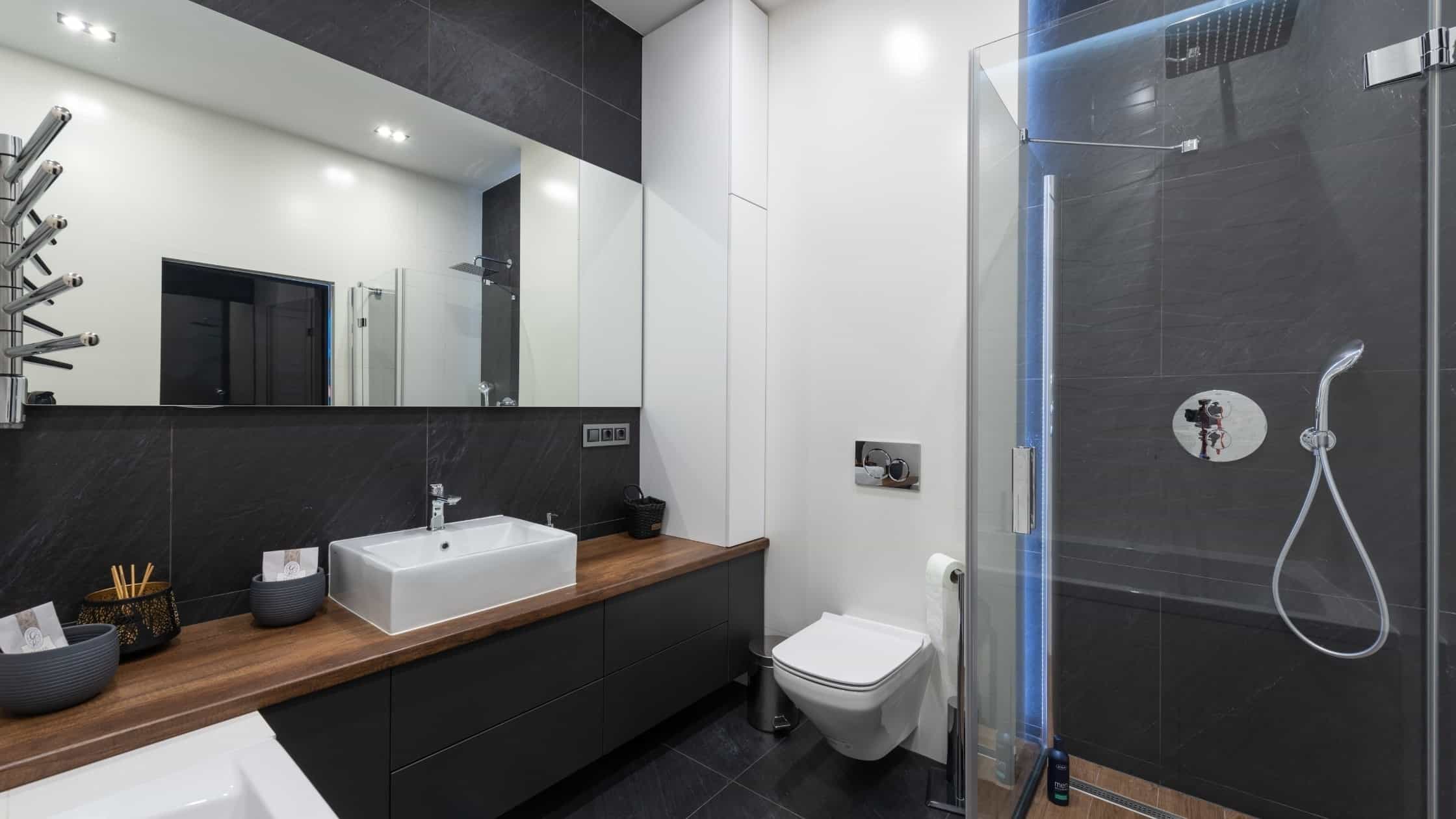 Bright modern bathroom with sleek black and white design, featuring a vanity, mirror, and shower.