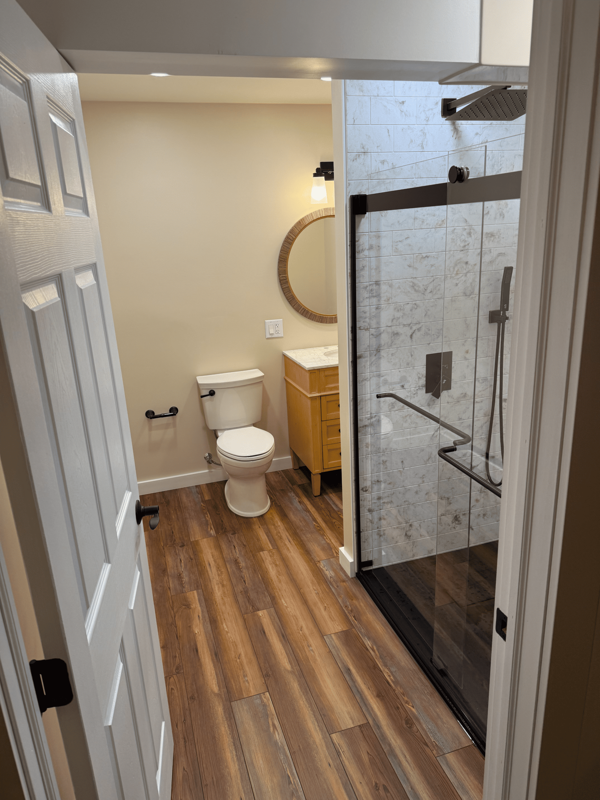 Bathroom with walk-in shower, toilet, and wooden vanity for home renovation.