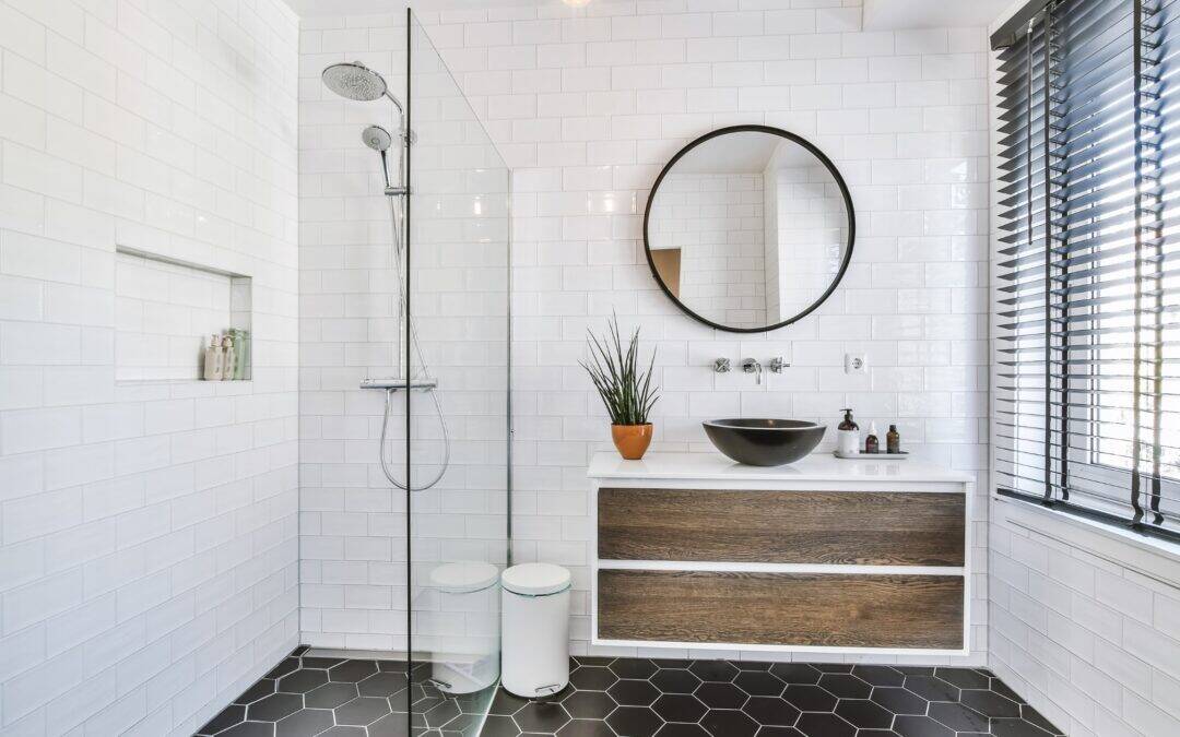 Stylish modern bathroom with walk-in shower, round mirror, and wooden vanity.
