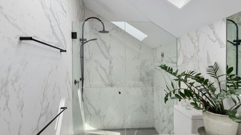 Modern bathroom shower with sleek black fixtures and marble walls, creating a luxurious and stylish.