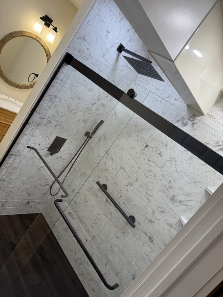 Stylish walk-in shower with black fixtures and glass enclosure in a contemporary bathroom.