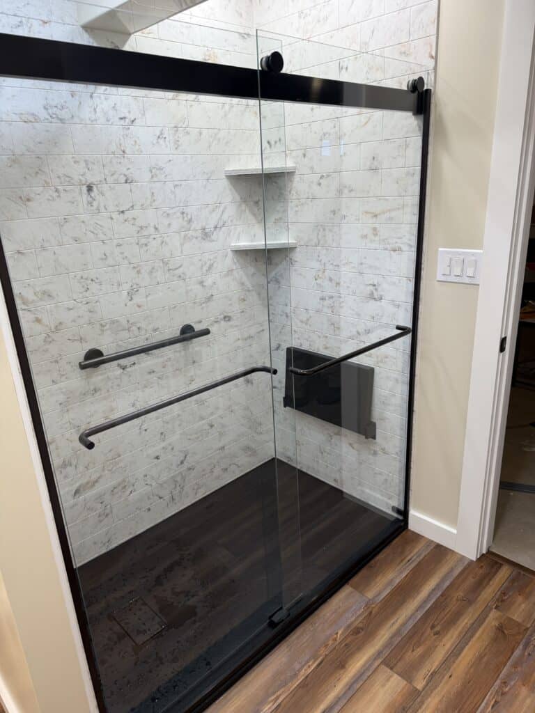 Walk-in shower with glass enclosure and built-in shelves.