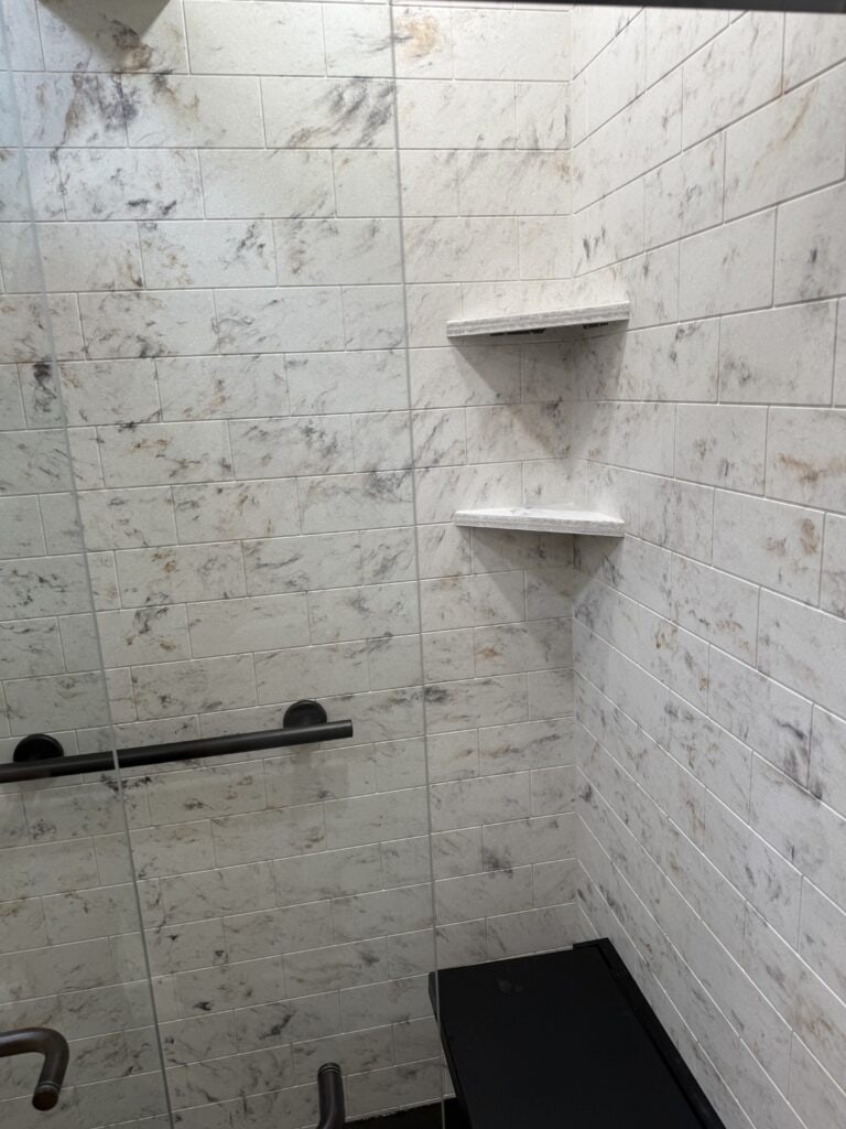 Modern shower niche with marble tiles and built-in shelves.