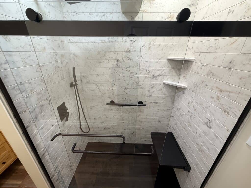 Accessible walk-in shower with grab bars and built-in shelves.