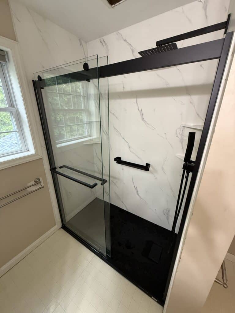 Modern walk-in shower with glass doors and black fixtures.
