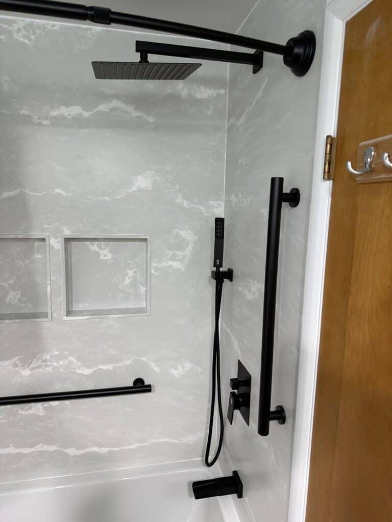 Shower system with rainfall showerhead, handheld shower, and safety grab bars in a contemporary bath.