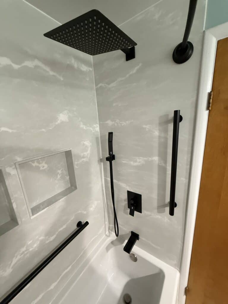 Shower system with rainfall showerhead, handheld shower, and safety grab bars in a sleek bathroom.