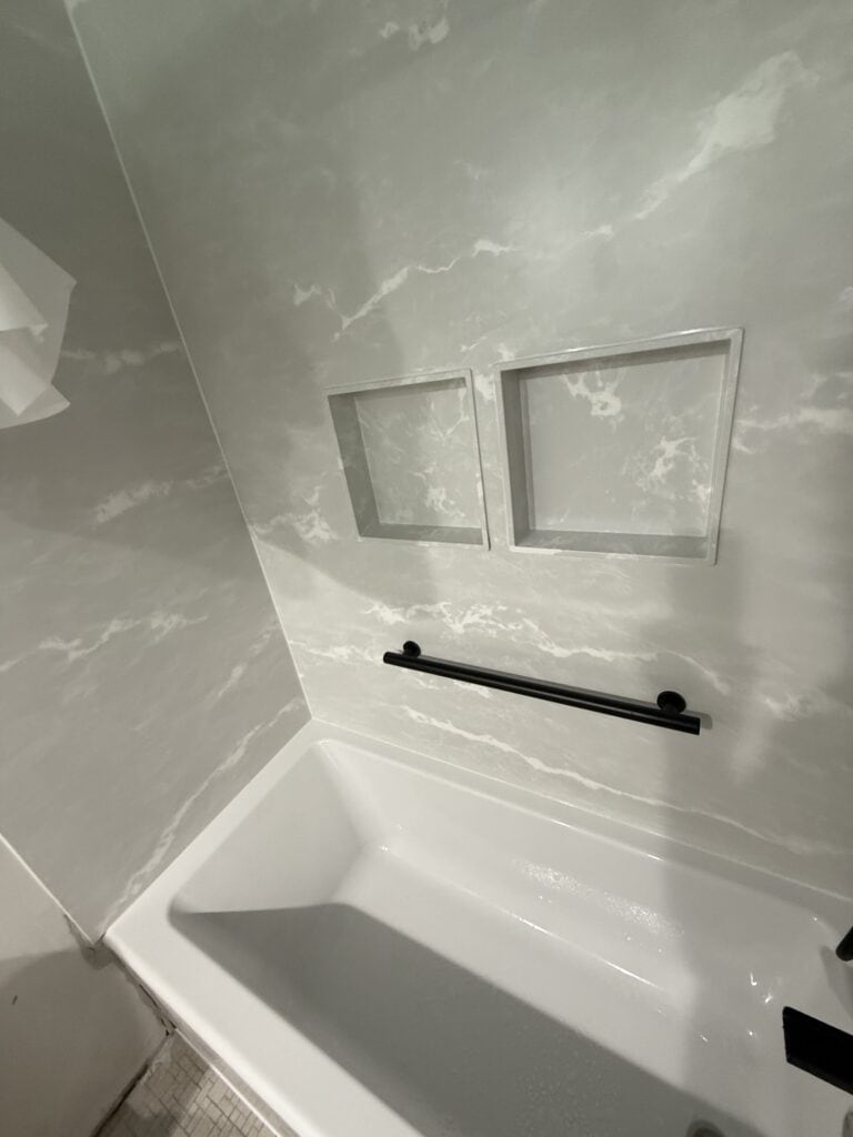 Modern bathroom with marble walls, built-in niches, and a sleek black towel bar.
