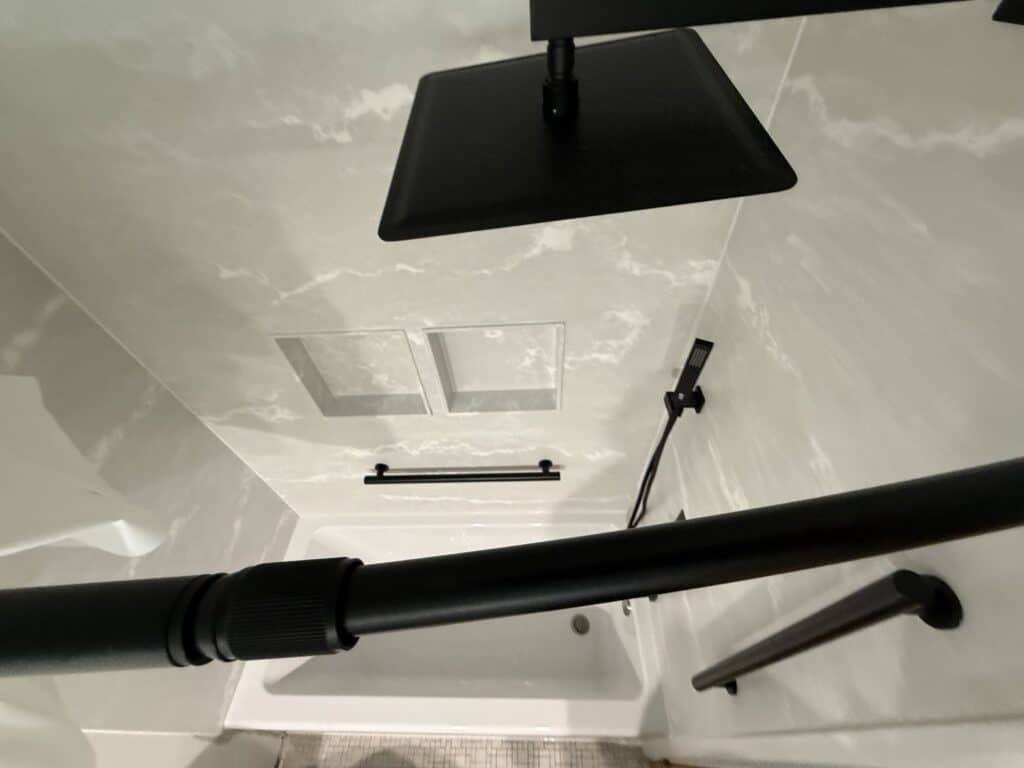 Modern black shower head and grab bar in a sleek bathroom.