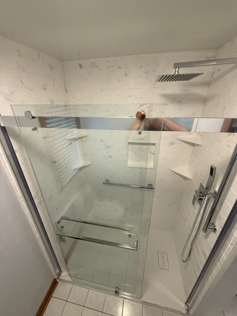 Accessible walk-in shower with glass enclosure and rainfall showerhead.