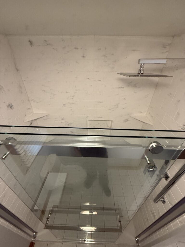 Shower enclosure with glass doors and chrome fixtures in a contemporary bathroom setting.