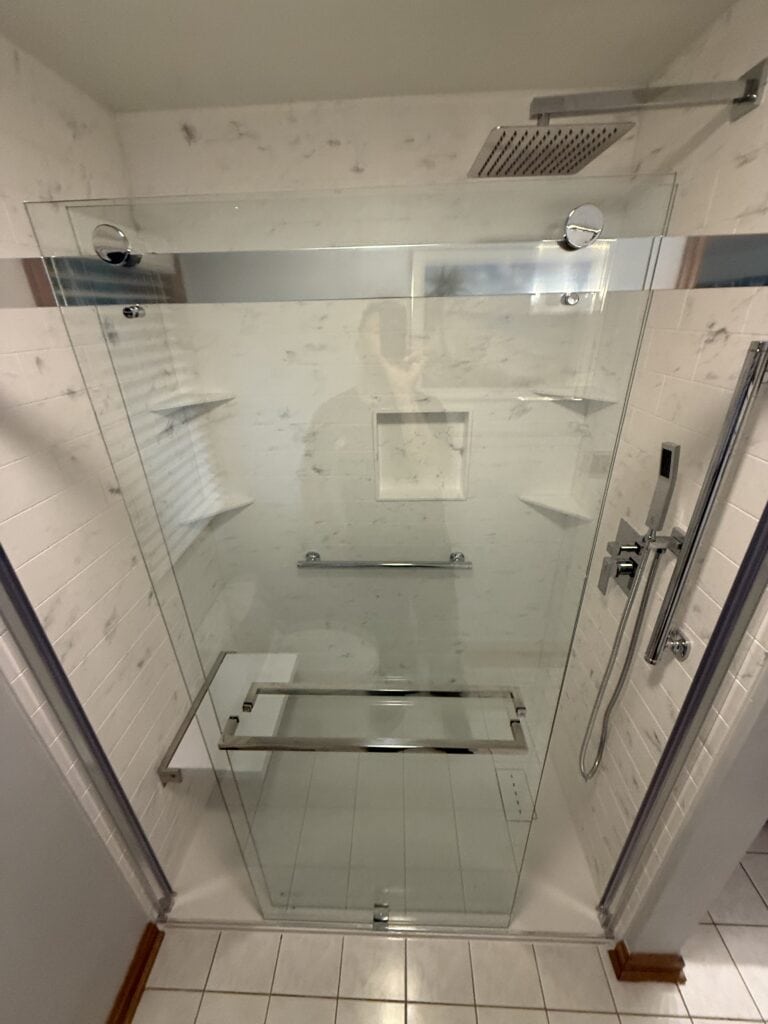 Accessible glass shower with built-in shelves and grab bar.