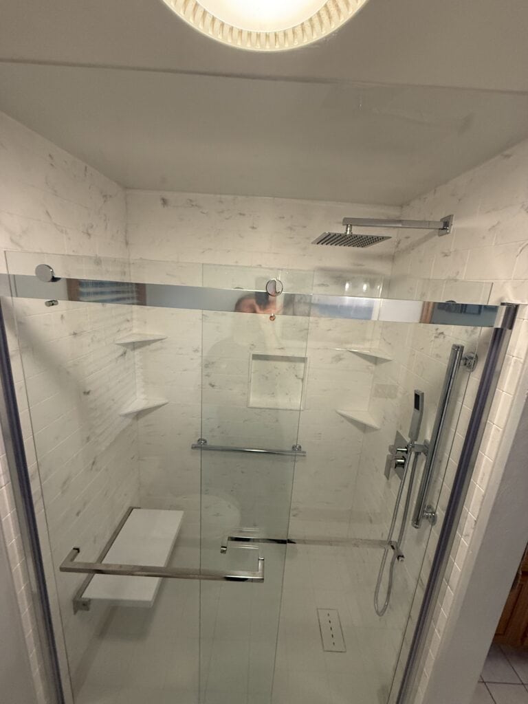 Accessible walk-in shower with glass doors and built-in shelves.