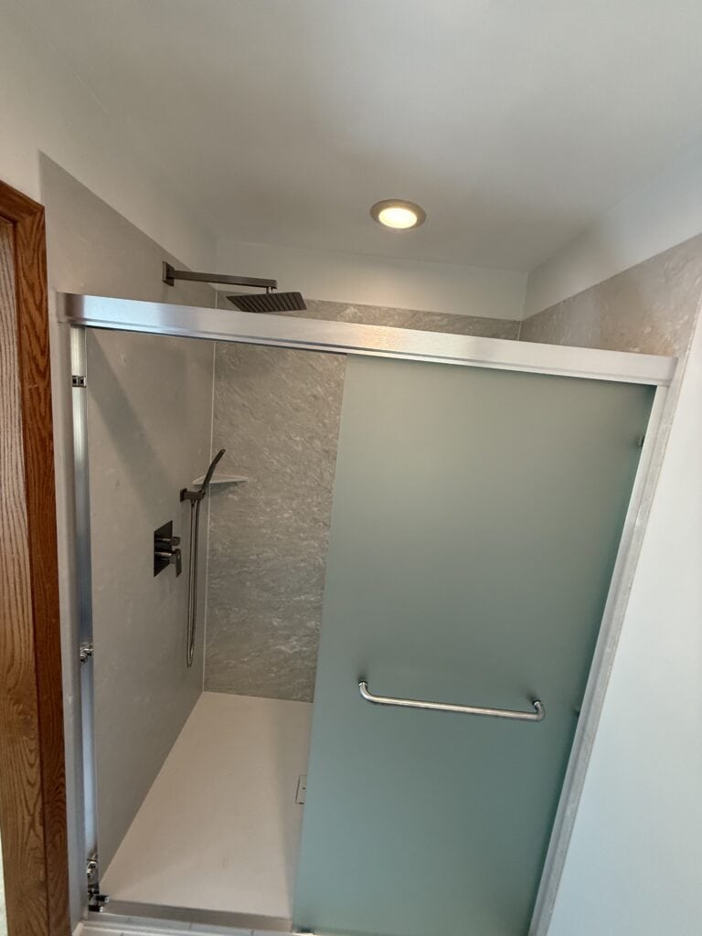 Accessible walk-in shower with frosted glass door.