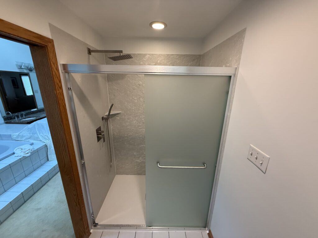 Accessible shower with frosted glass door and modern fixtures.