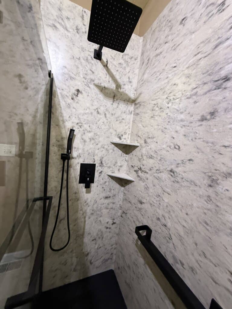 Elegant walk-in shower with rainfall showerhead and built-in corner shelves.