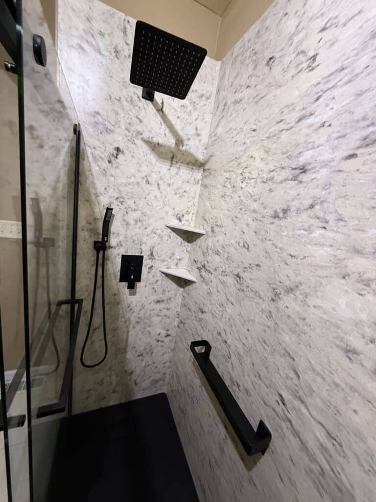 Modern shower with rainfall head, handheld shower, and wall-mounted shelves in a sleek bathroom.