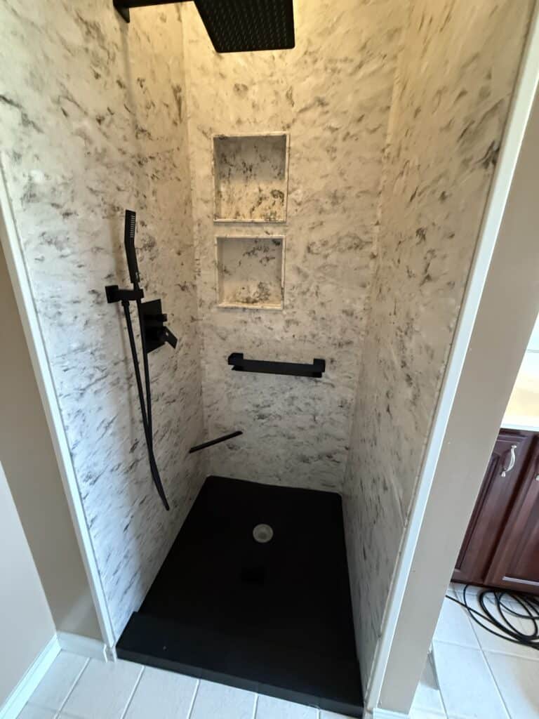 Shower with built-in shelves and black fixtures in a contemporary bathroom.