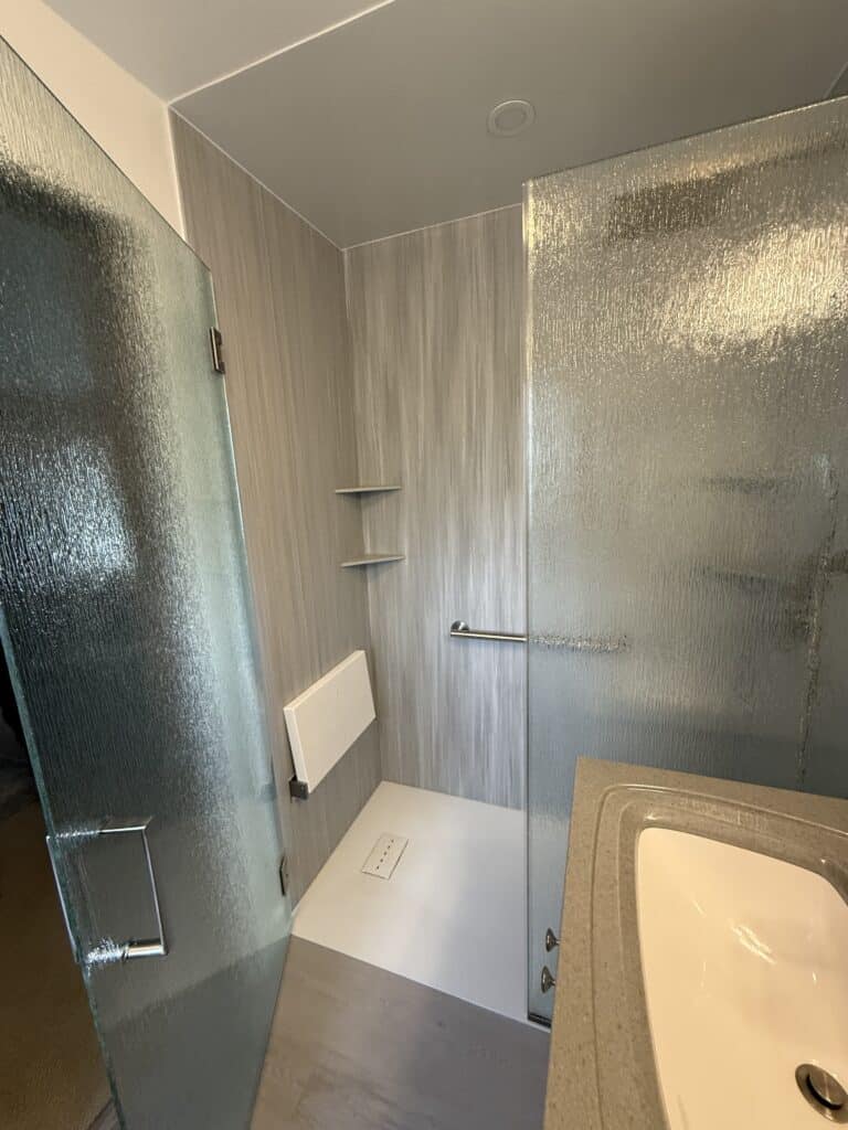 Accessible shower with textured walls and safety grab bar.