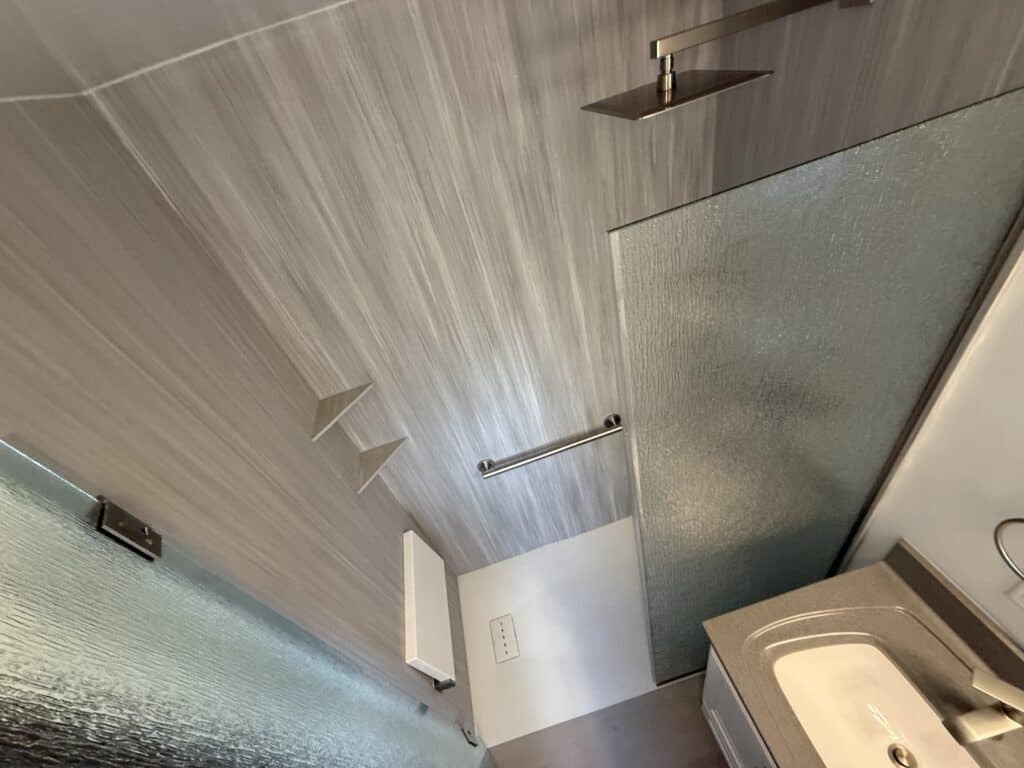 Modern walk-in shower with rainfall showerhead and glass door.