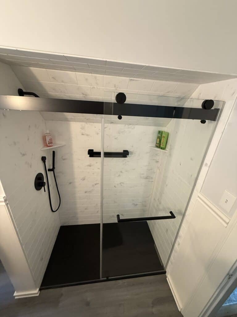 Shower enclosure with black hardware and glass doors, modern bathroom design.