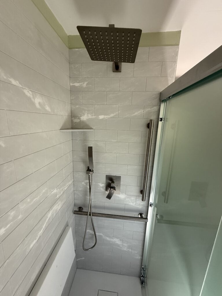 Modern walk-in shower with rainfall showerhead and glass door.