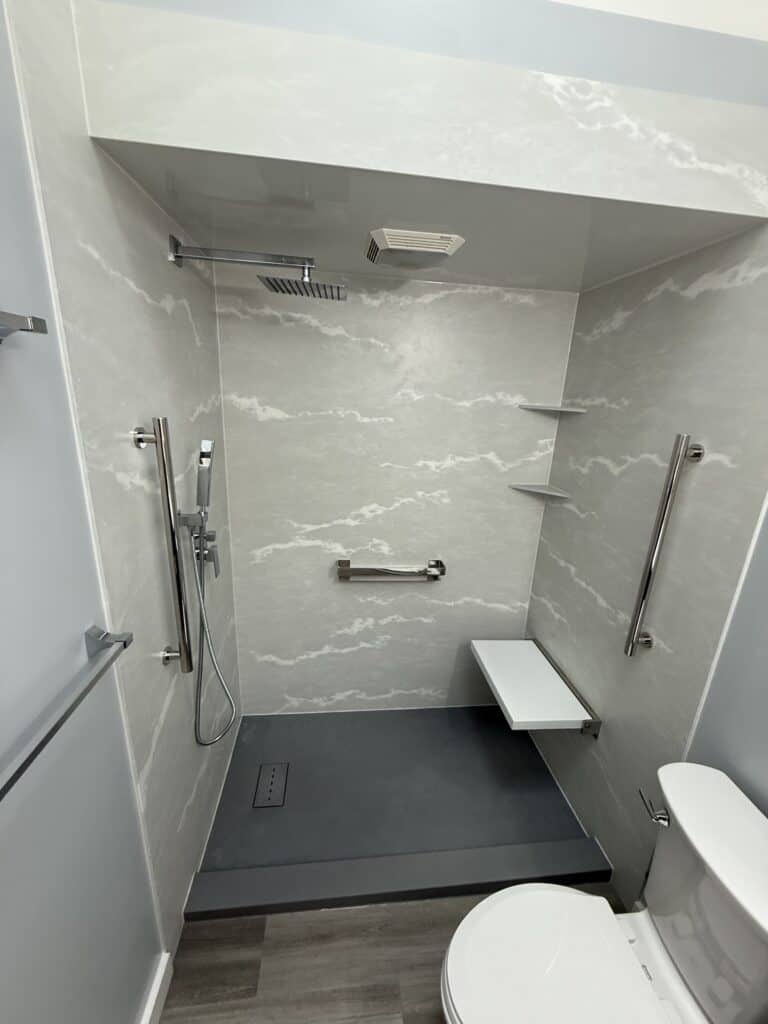 Accessible shower with grab bars and a fold-down seat for safety and convenience.