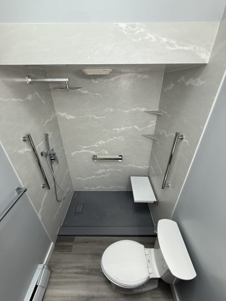 Modern accessible bathroom with shower seat, grab bars, and non-slip flooring for safety.