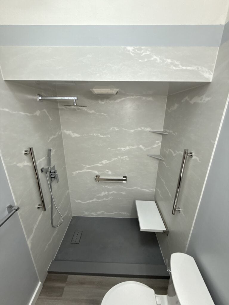 Accessible shower with grab bars and fold-down seat for safety and convenience.