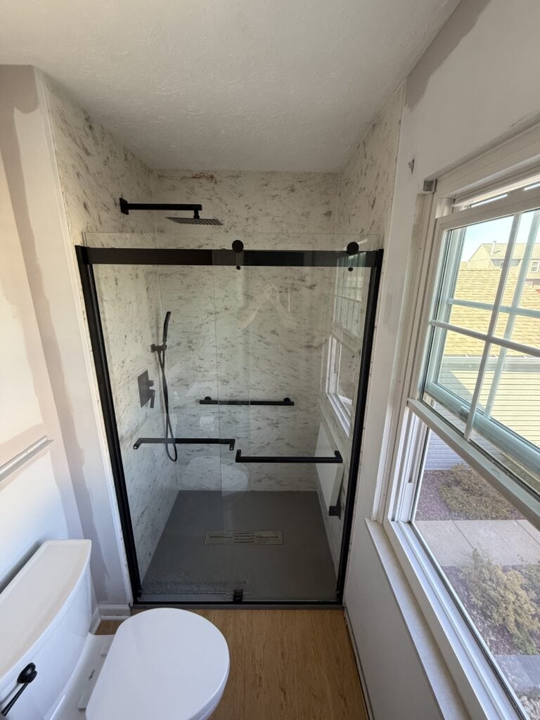 Glass shower enclosure with black hardware.