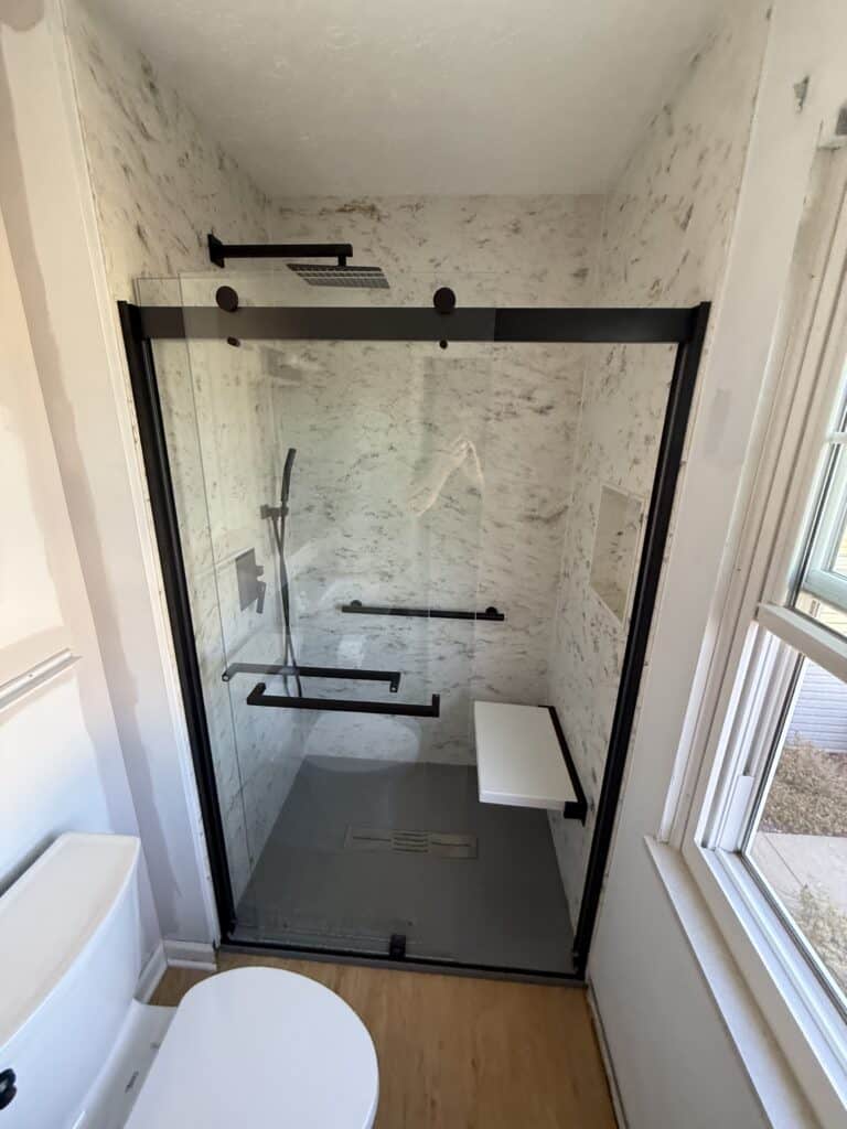 Accessible walk-in shower with glass door and built-in bench.