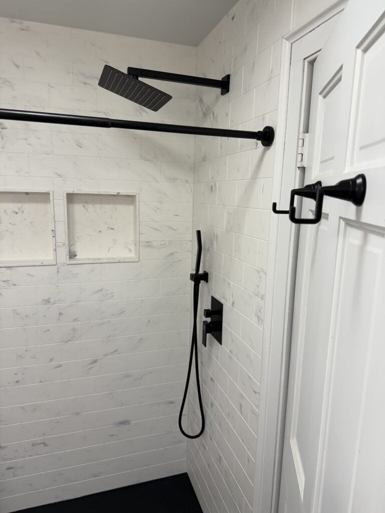 Shower with black fixtures, rainfall showerhead, and built-in wall niches for toiletries.