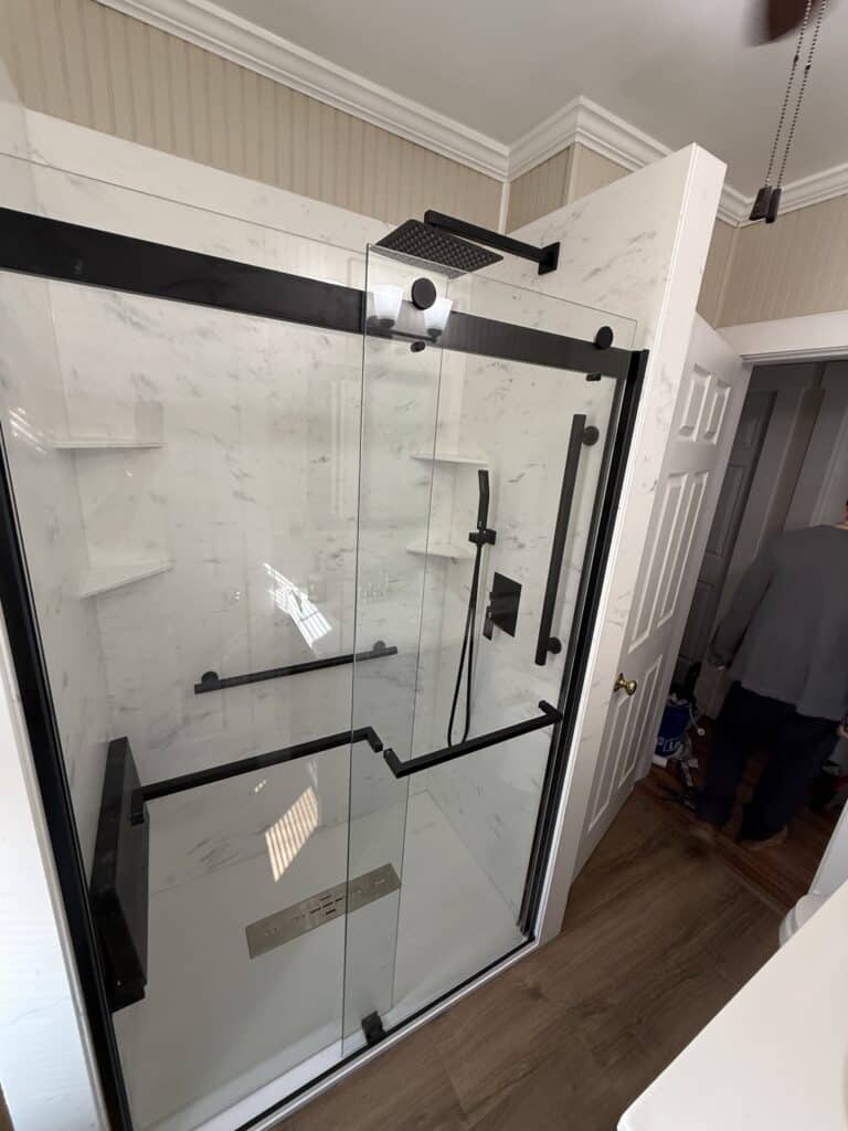 Accessible walk-in shower with black fixtures and glass doors.