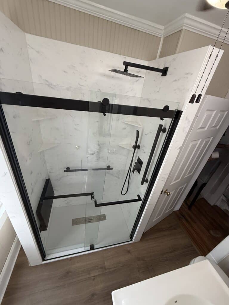 Stylish walk-in shower with black fixtures and glass doors in a contemporary bathroom.