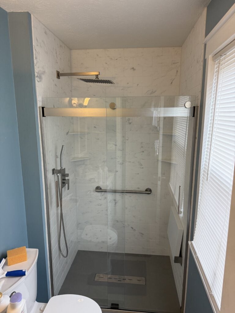 Walk-in shower with glass enclosure and rainfall showerhead.