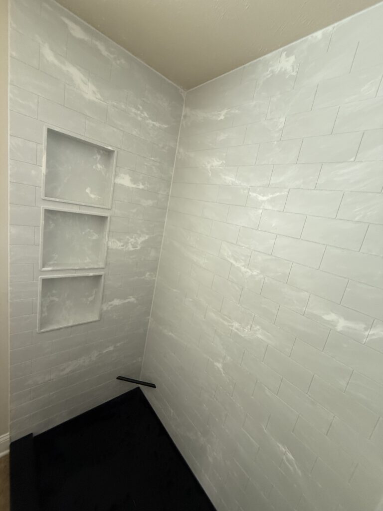 Shower niche with three shelves for toiletries, built into a tiled bathroom wall.