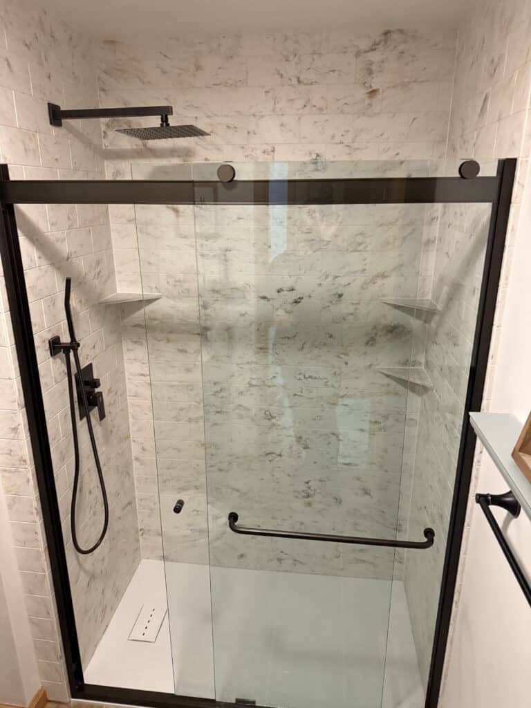 Accessible walk-in shower with glass doors and black fixtures.