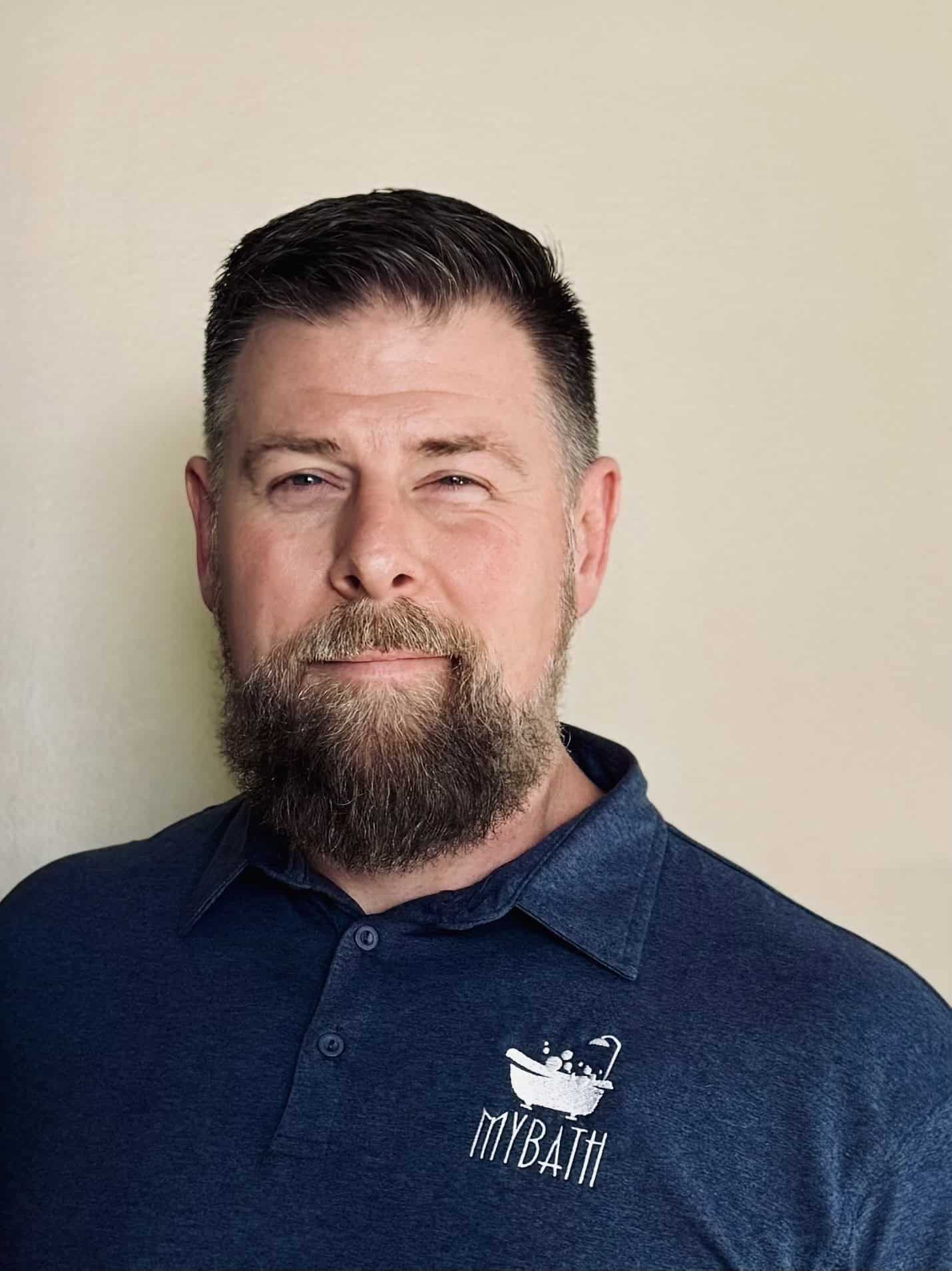 Professional man with beard wearing My Bath LLC polo shirt, smiling confidently.