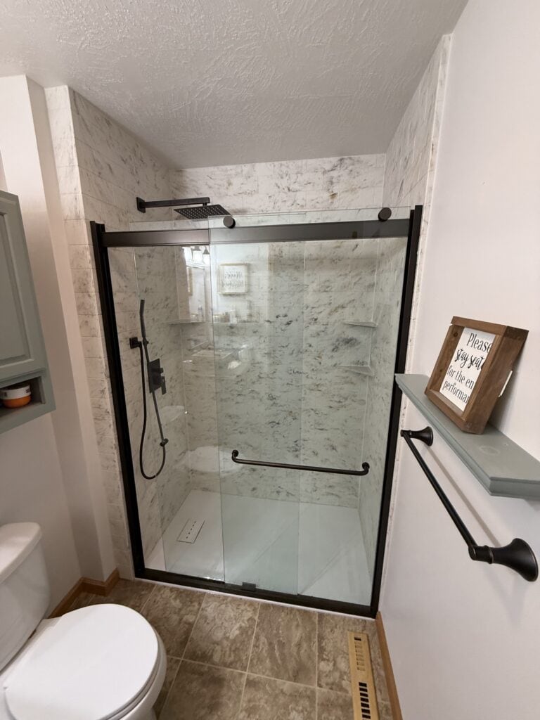 Accessible walk-in shower with glass doors and grab bars.