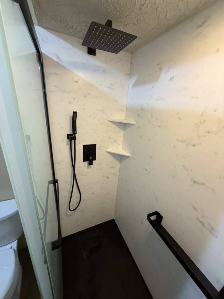 Modern walk-in shower with rainfall and handheld showerheads.