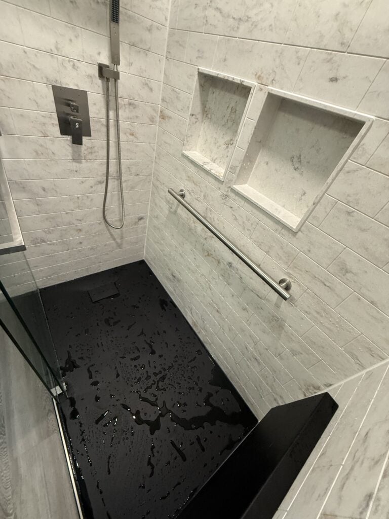 Modern walk-in shower with built-in niches and grab bar.