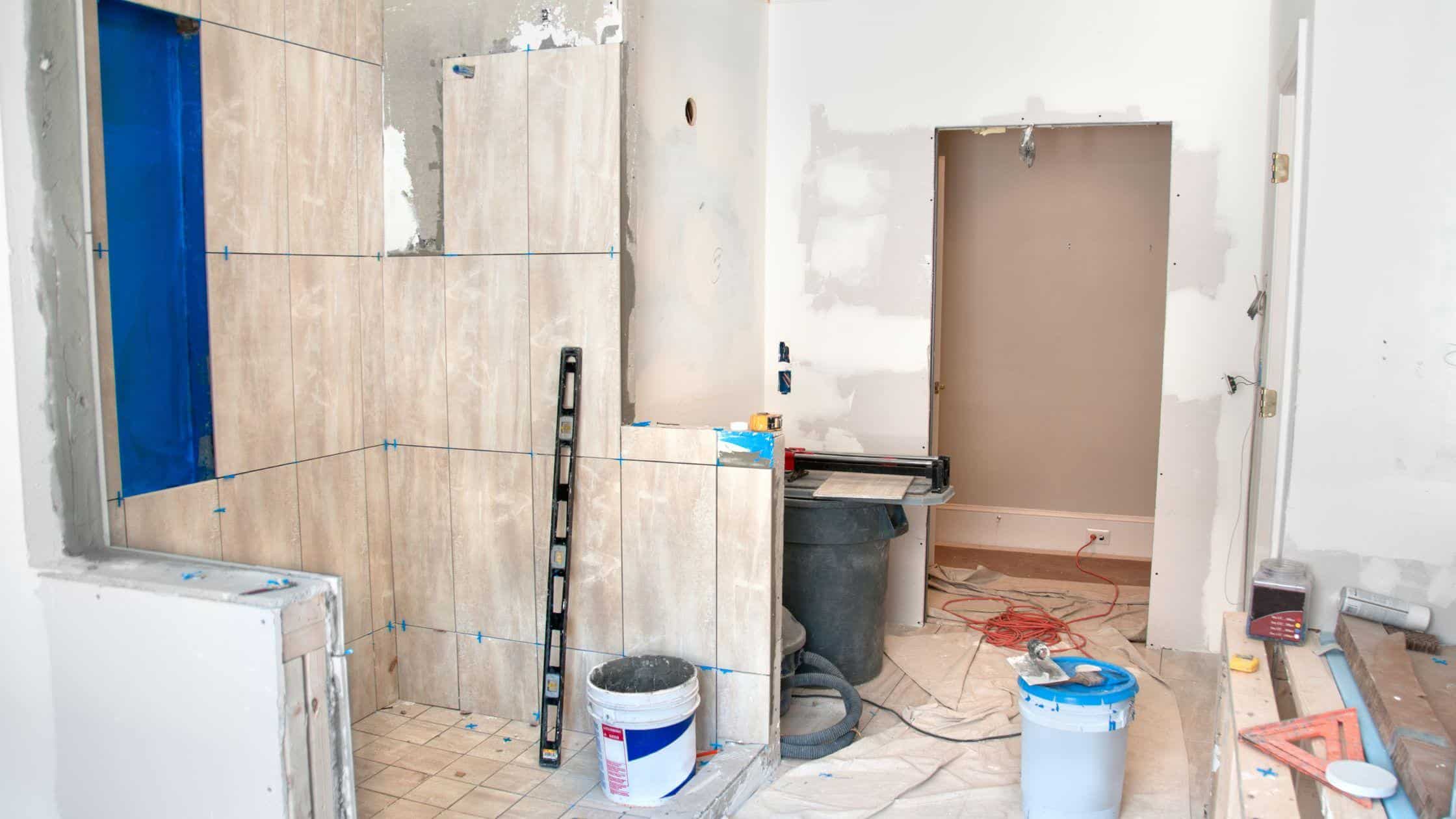 Interior view of a bathroom under renovation with tiles, tools, and construction materials.