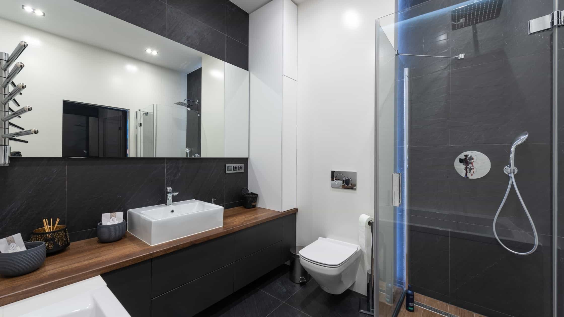 Bright modern bathroom with sleek black and white design, featuring a walk-in shower, vanity, and to.