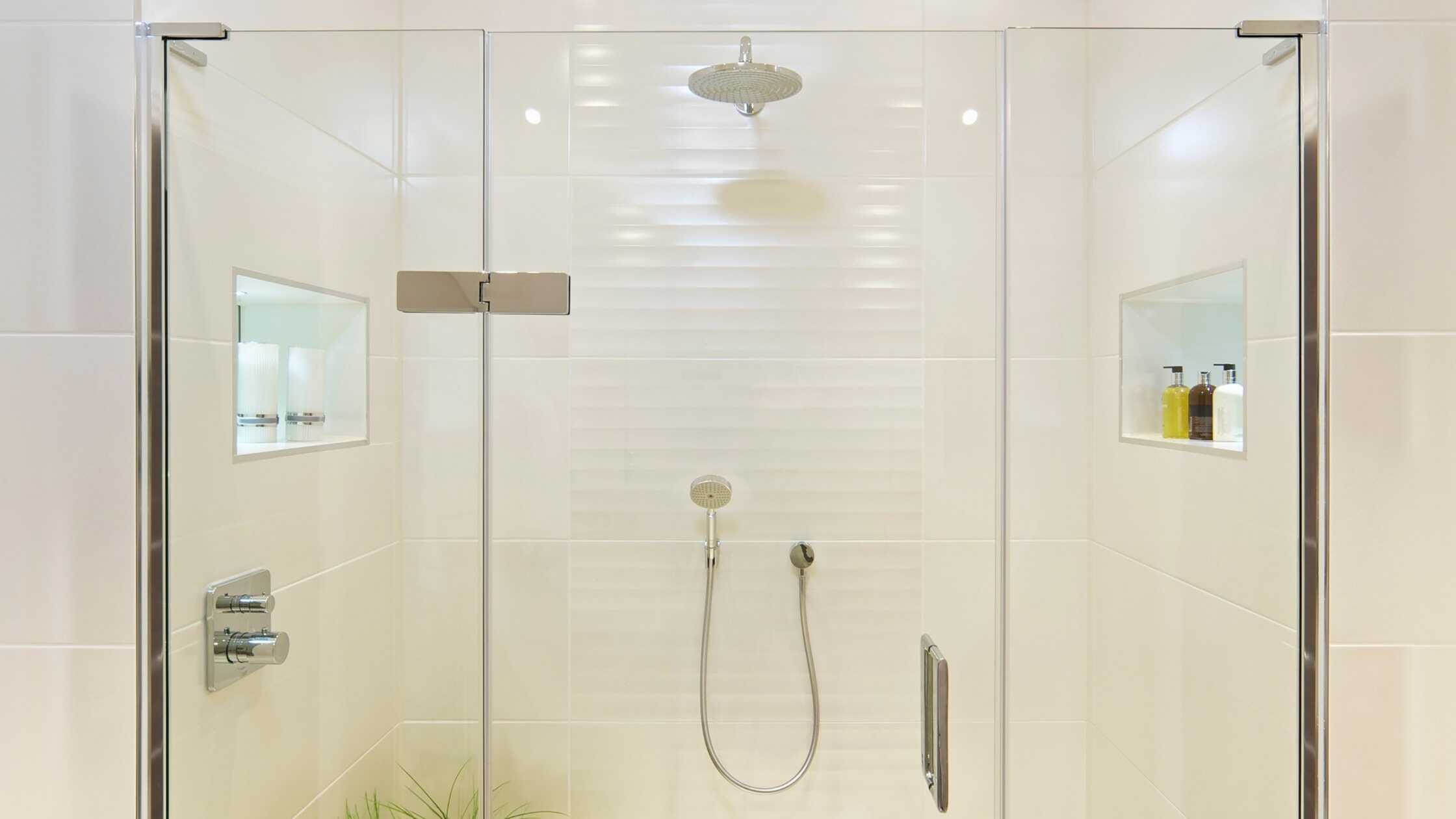 Elegant walk-in shower with glass doors and built-in niche storage.
